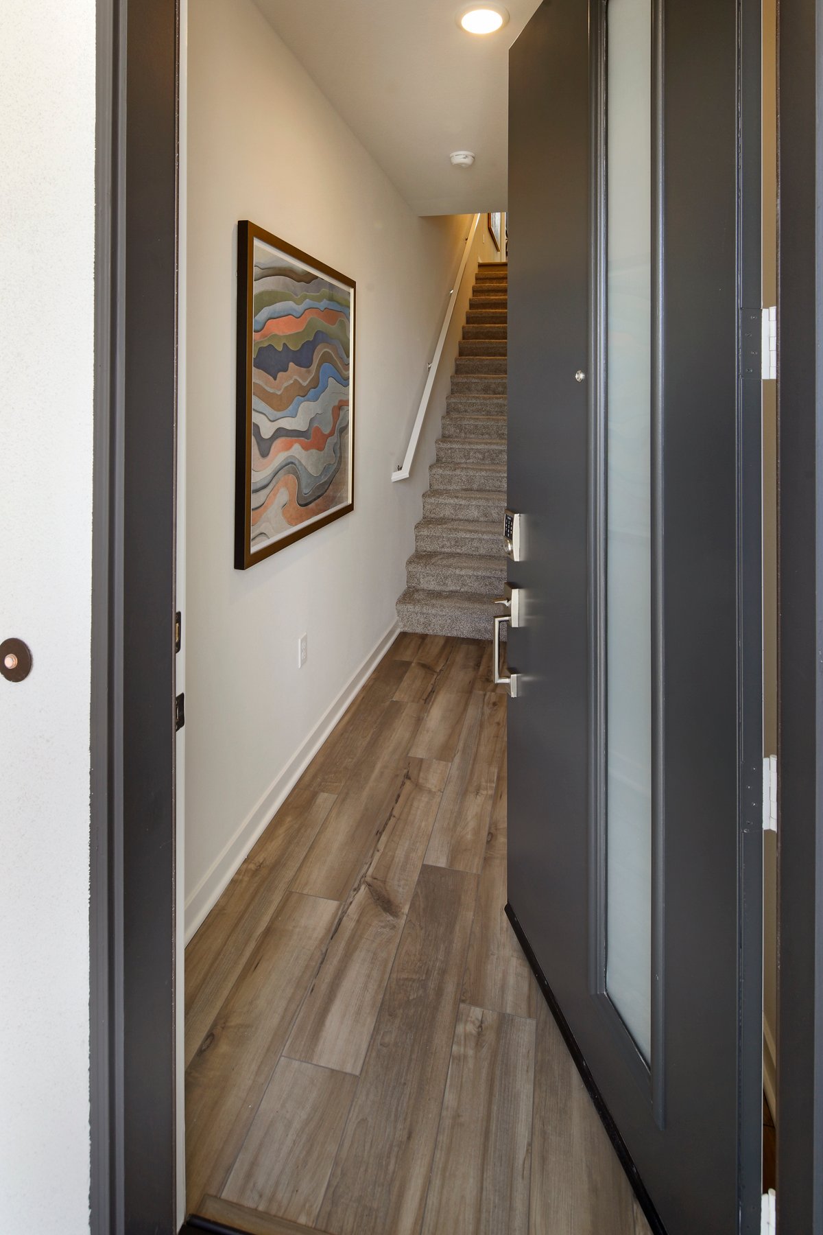 A hallway with a wood floor and a painting on the wall.