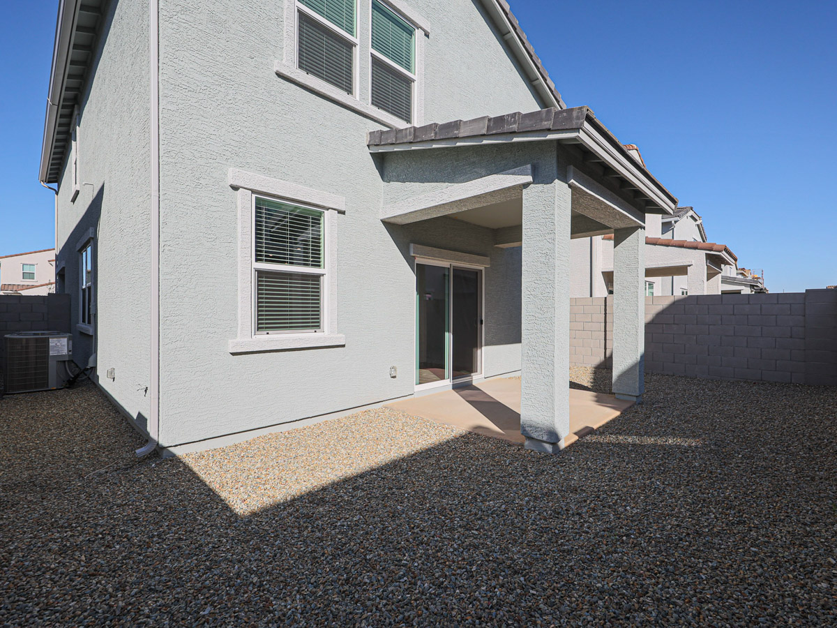A white house with a stone patio.
