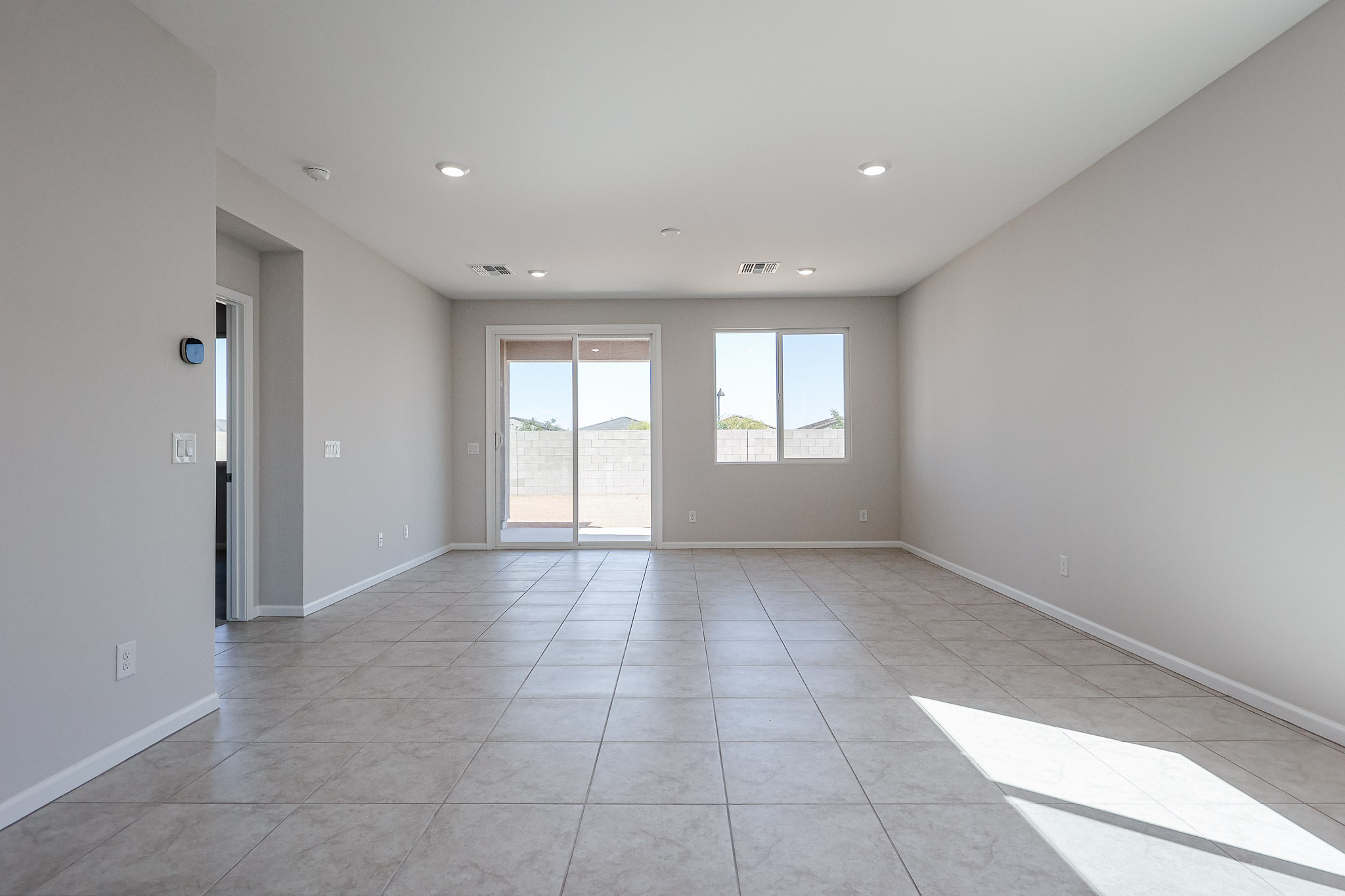 A large empty room with a tile floor and windows.