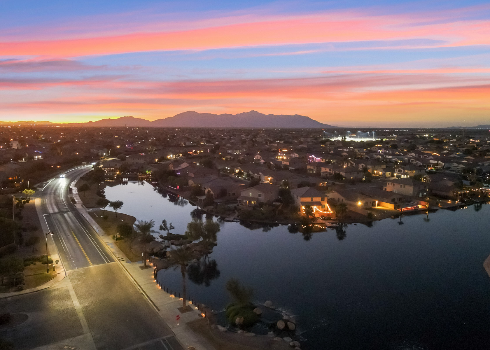 A road with a body of water and buildings along it.