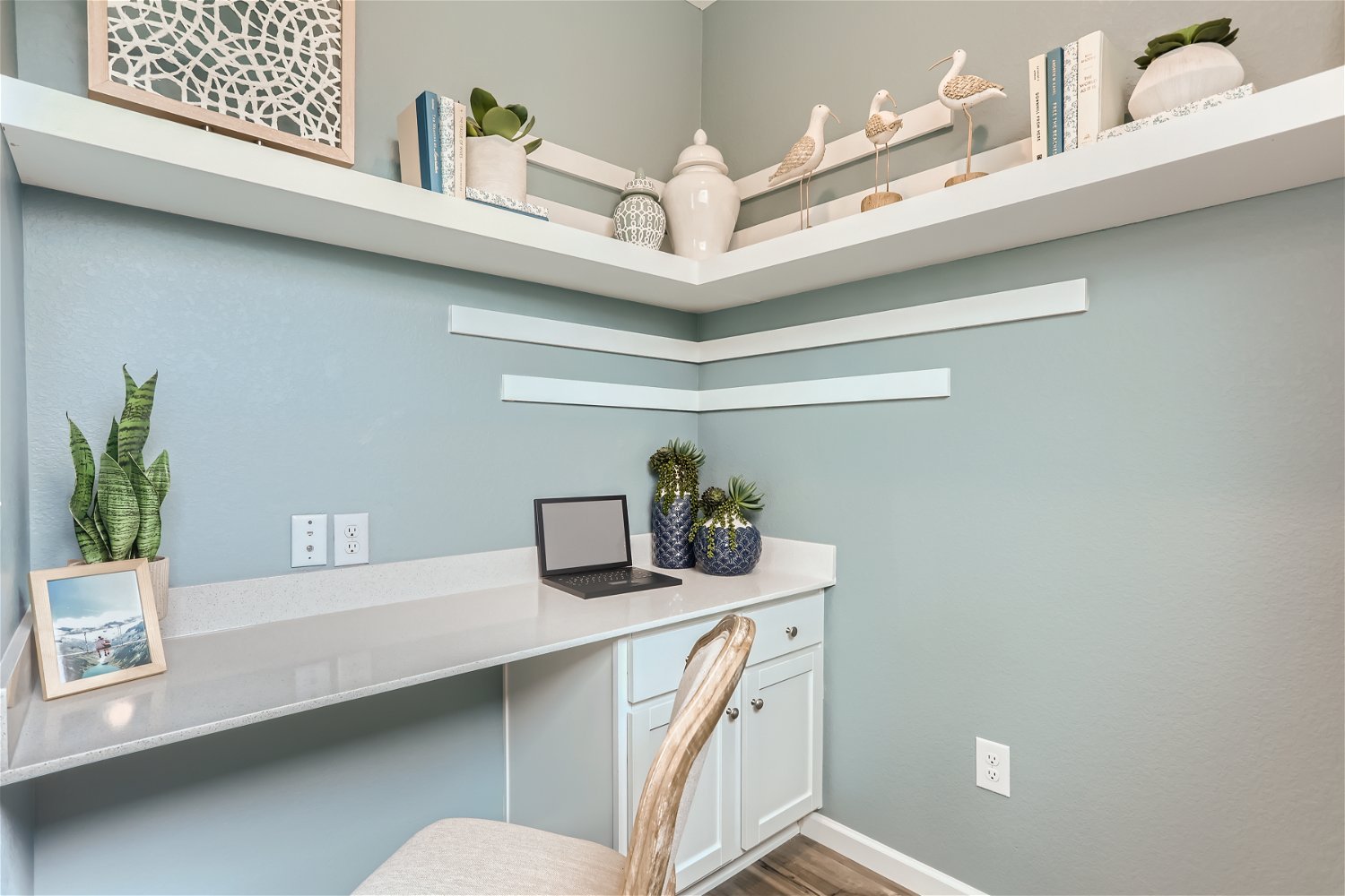A white desk with a laptop and a chair in a room with white walls.