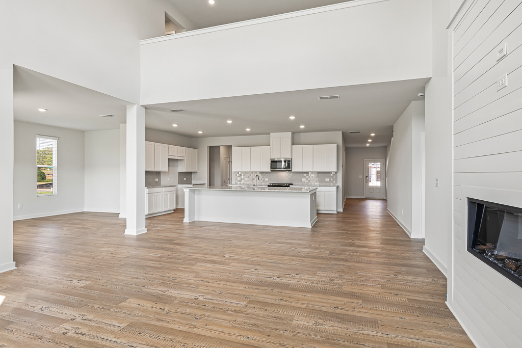 A large white kitchen with a wood floor.