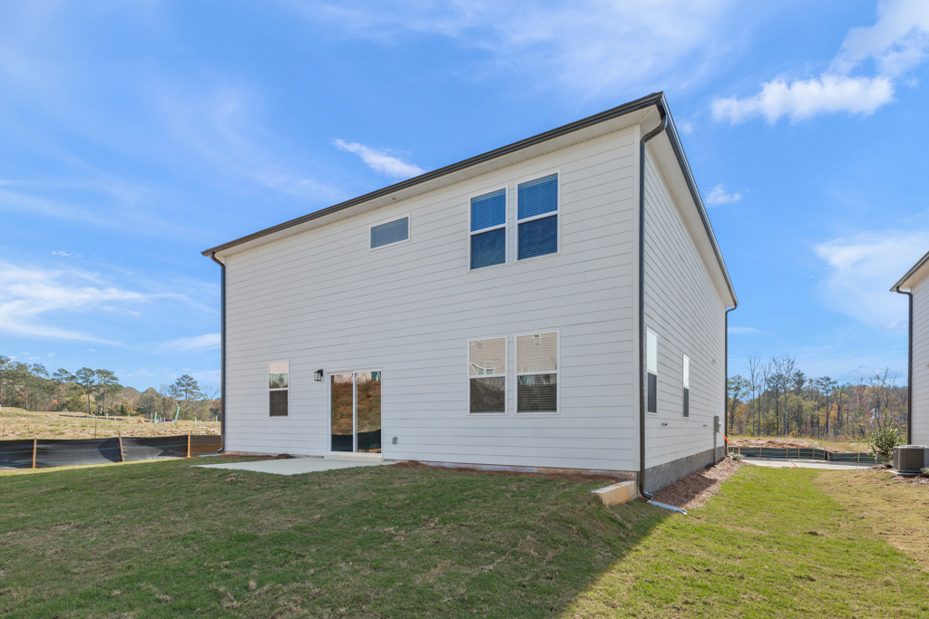 A house with a grass yard with Rockingham Meeting House in the background.