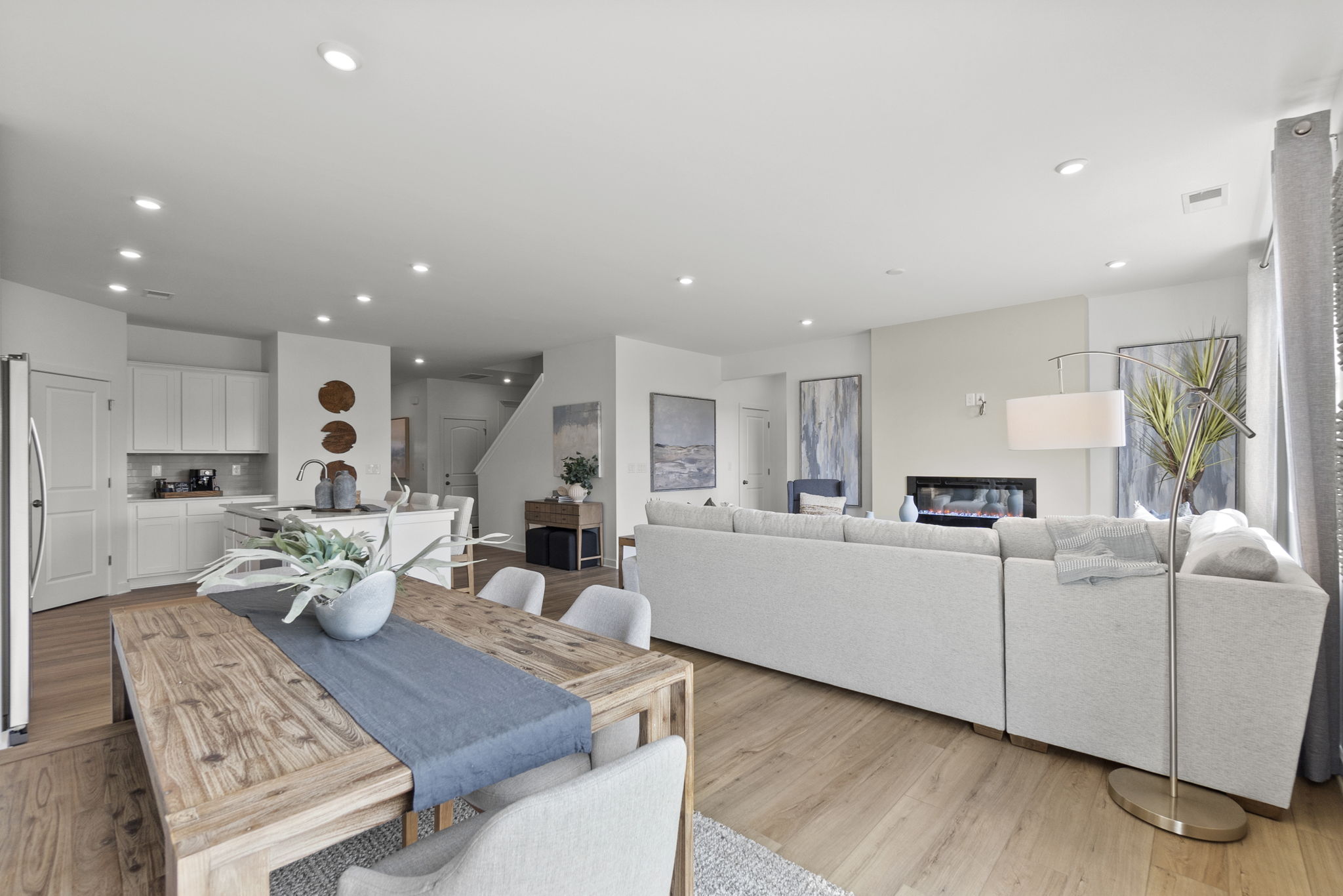 A large living room with a large white couch and a dining table.