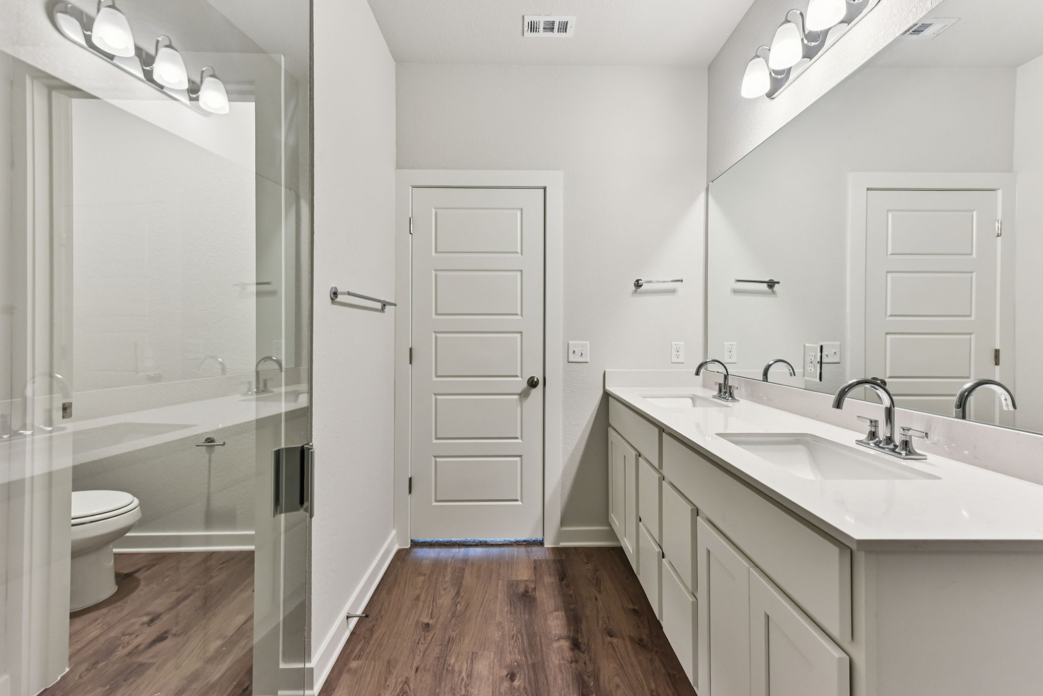 A bathroom with a sink toilet and mirror.