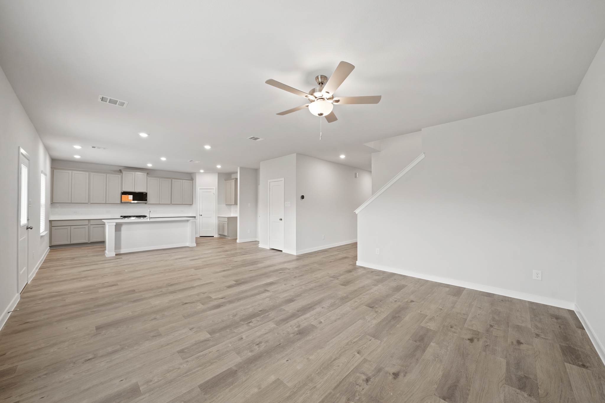 A large empty room with a ceiling fan and a wood floor.
