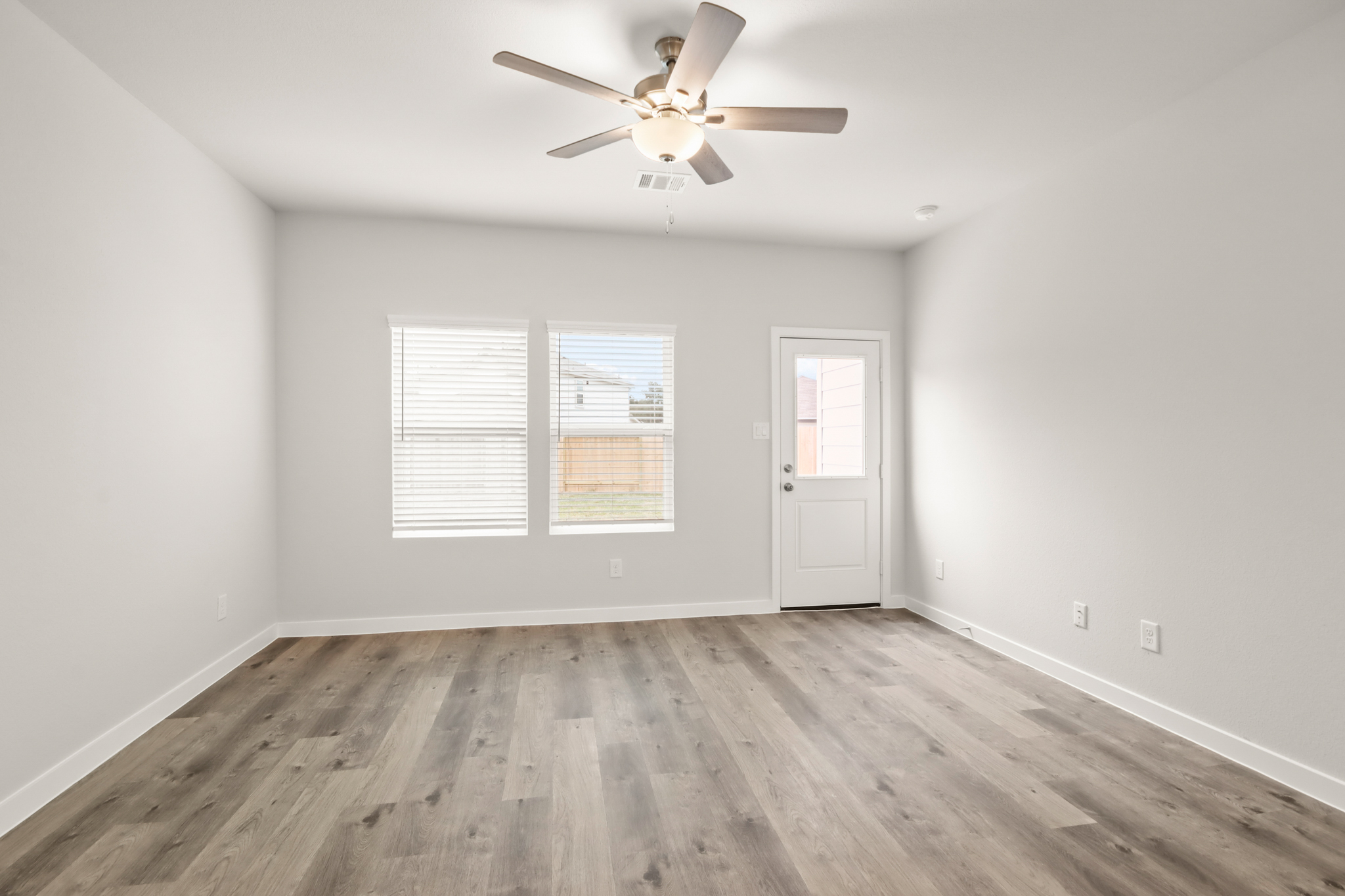 A room with a ceiling fan and a wood floor.