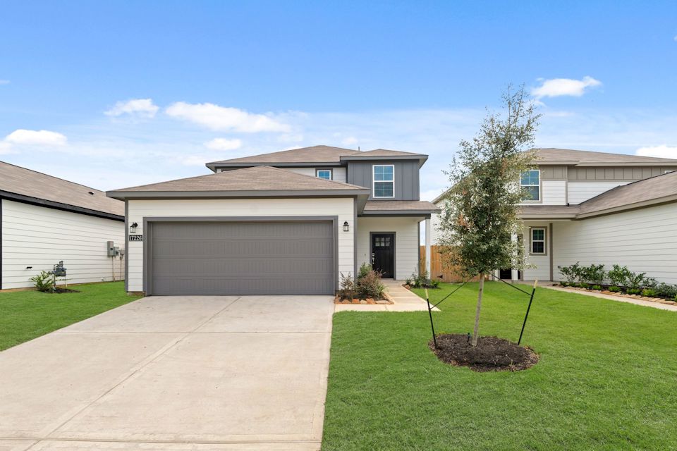 A house with a garage and a tree in the front.