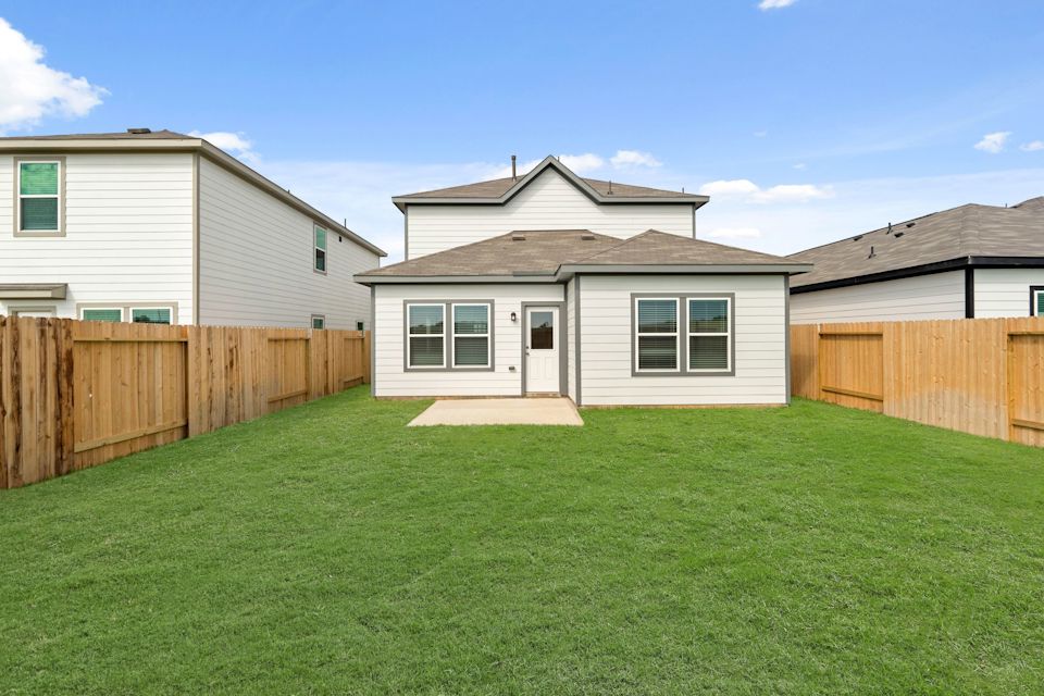 A backyard with a fence and a house.