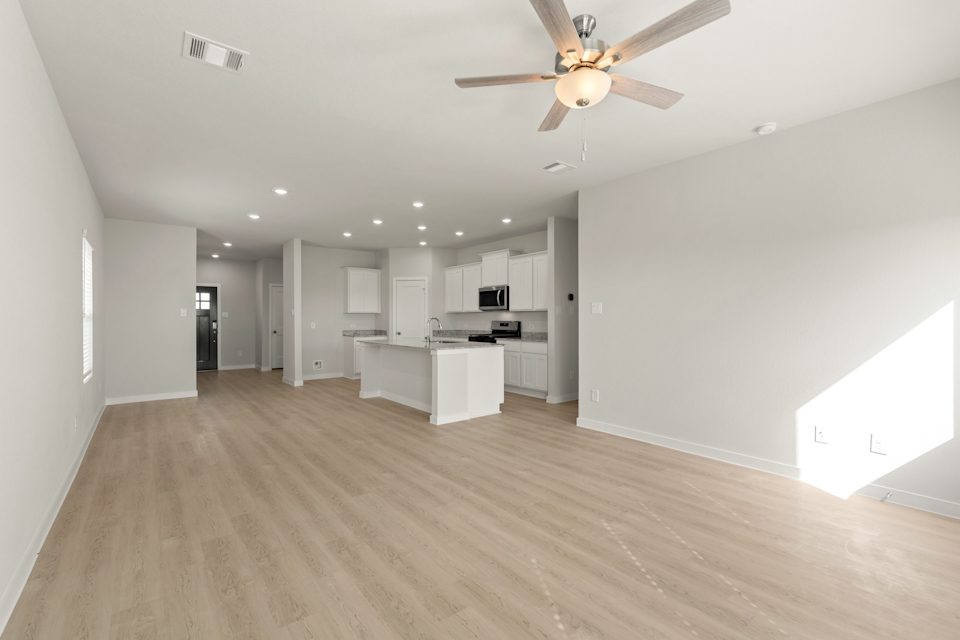 A large empty room with a wood floor and a ceiling fan.