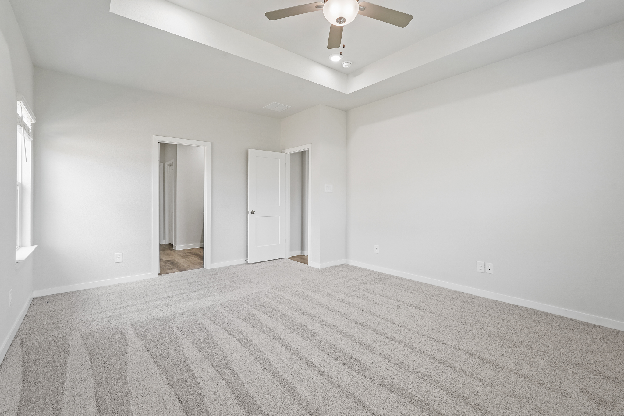 A room with a carpet and a ceiling fan.