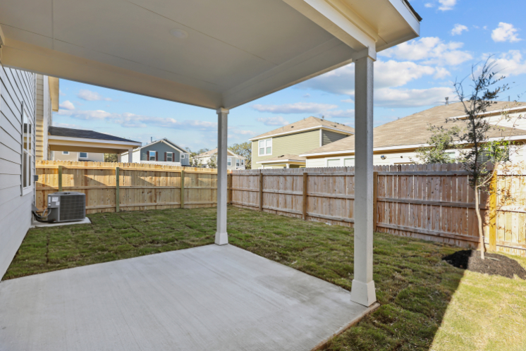 A deck with a fence and a house in the background.