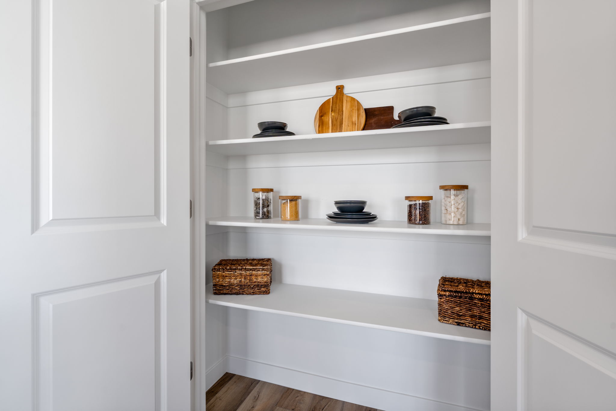A white shelving unit with white cabinets and white walls.