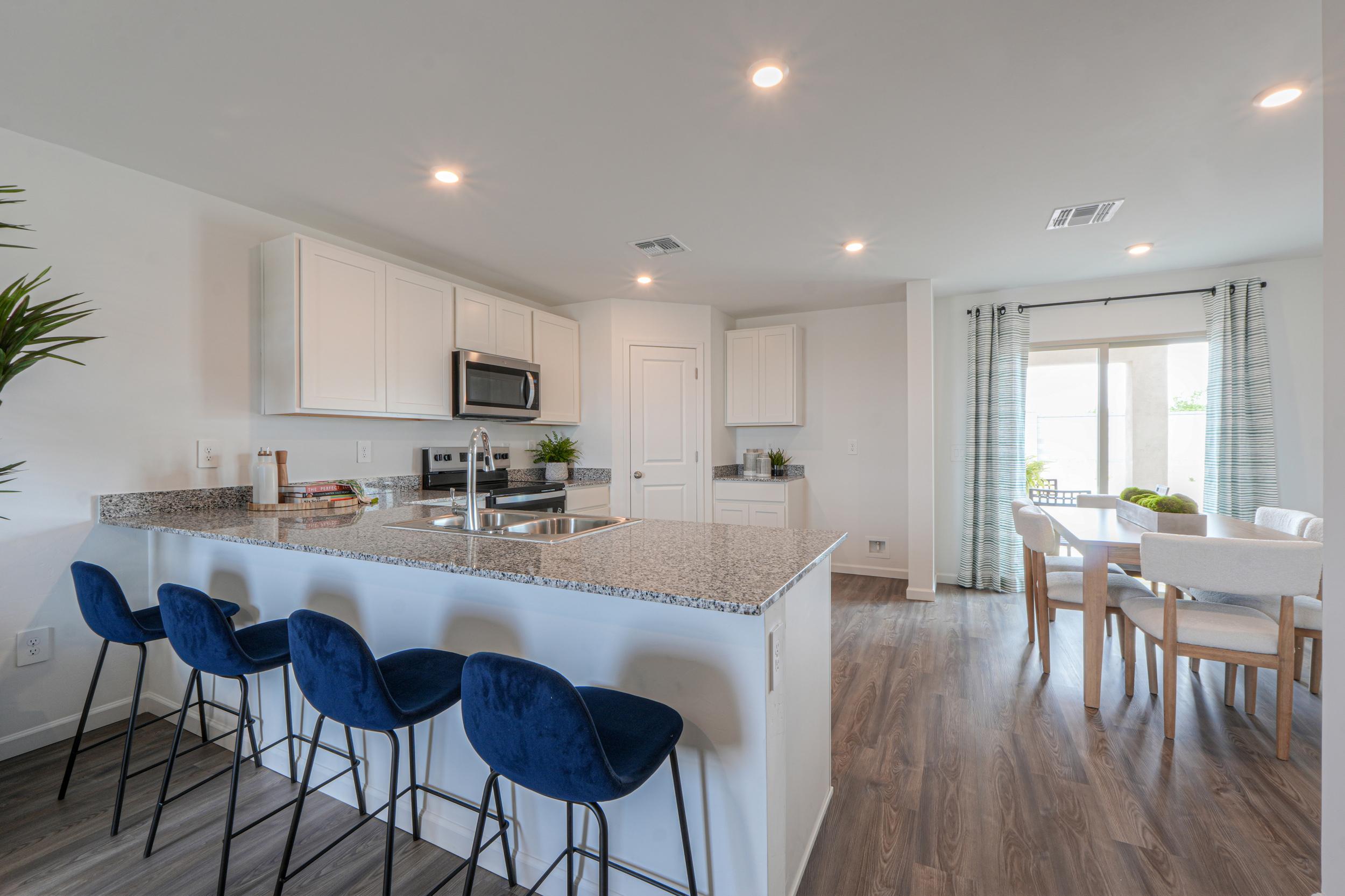A kitchen with a bar and chairs.