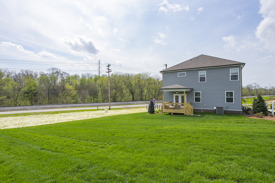 A house with a lawn and trees in the back.